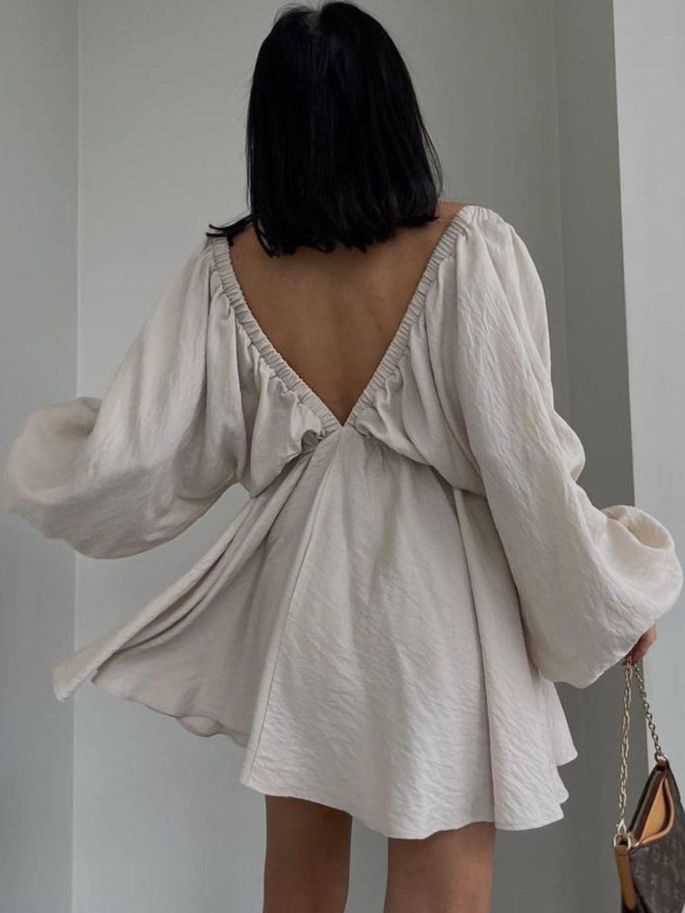 Beige ruched V-neck dress with balloon sleeves and a low back.