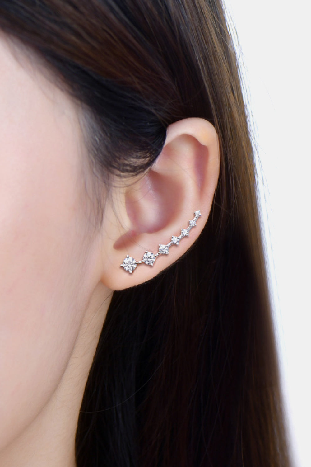 Silver ear climbers with sparkling diamond accents, climbing the ear.