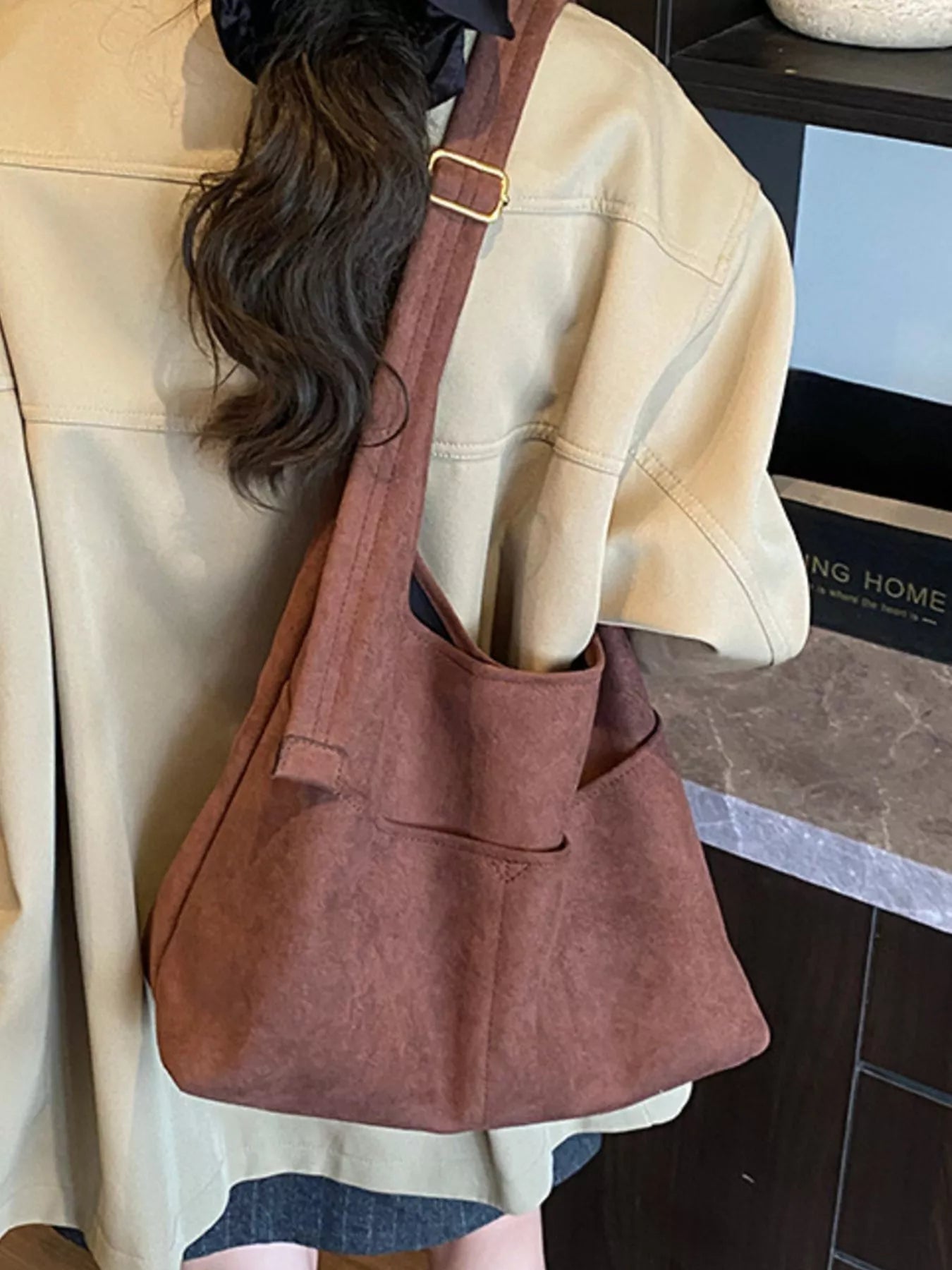 Large brown suede shoulder bag with adjustable strap and exterior pockets.