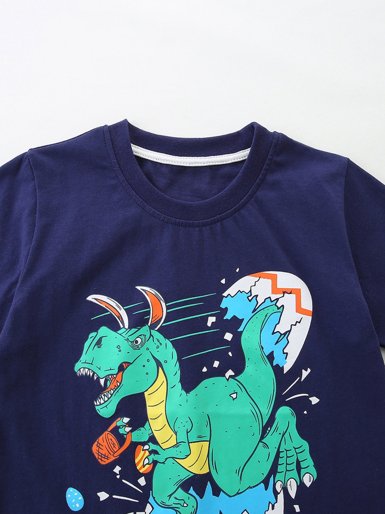 Navy cotton toddler t-shirt with a green dinosaur hatching from an egg graphic.