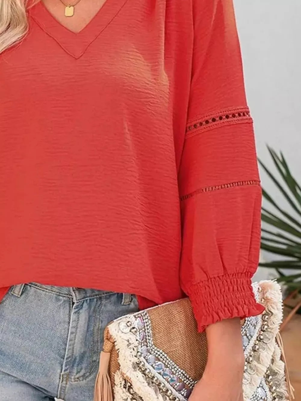 Red smocked long sleeve blouse with V-neck and eyelet detail on sleeves.