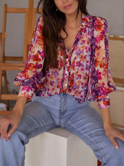 Vibrant floral print button-up shirt with long sleeves and a collared neckline.