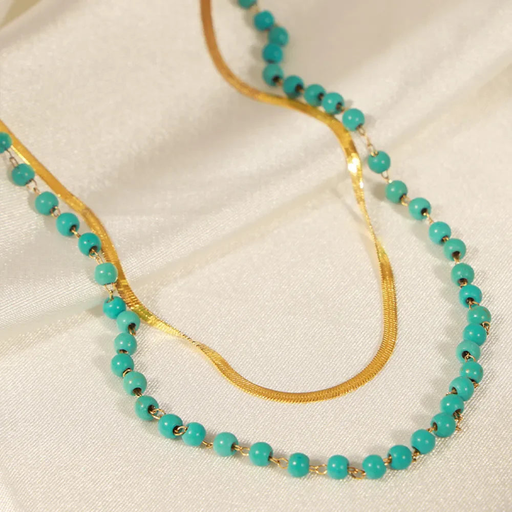 Gold layered necklace with turquoise beads and a snake chain.