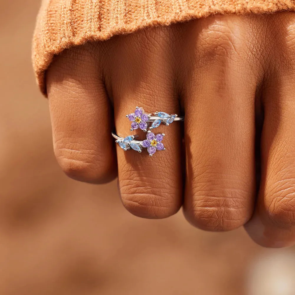 Silver bypass ring with purple and blue floral zirconia accents.