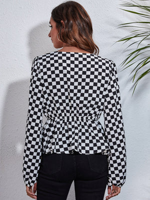 Black and white checkered peplum blouse with gathered waist and long sleeves.