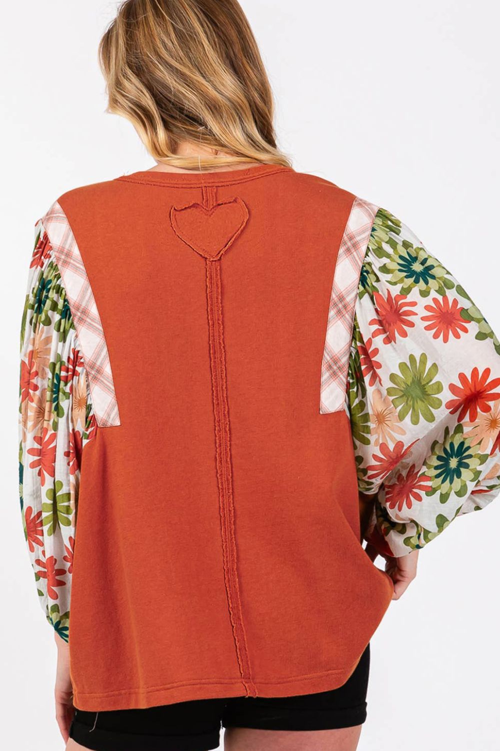 Orange-red blouse with floral patchwork balloon sleeves and heart detail on back.