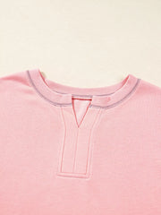 Dusty pink oversized sweatshirt with contrast stitching and a V-neck detail.