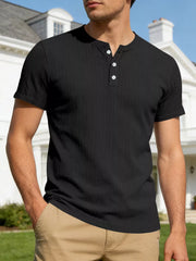 Black ribbed henley t-shirt with short sleeves and button placket, worn by a man.
