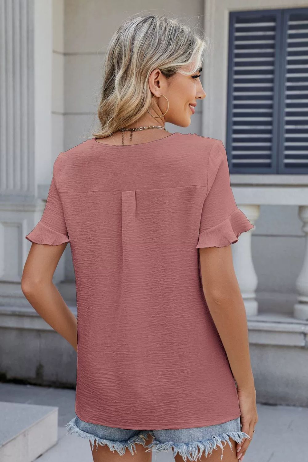 Dusty pink textured blouse with ruffle sleeves and a V-neckline.