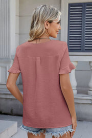 Dusty pink textured blouse with ruffle sleeves and a V-neckline.