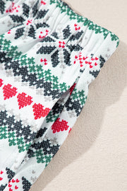 White cotton pajama shorts with a festive fair isle pattern of red hearts and green/black trees.