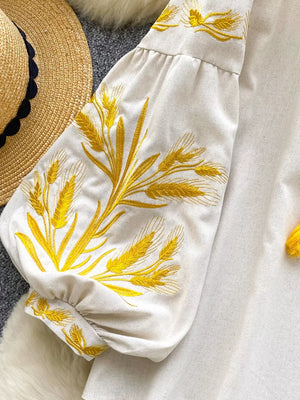 White embroidered tie-neck blouse with wheat detail on sleeve and cuff.