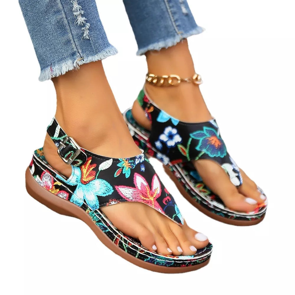 Black embroidered floral thong wedge sandals with adjustable ankle strap and buckle.