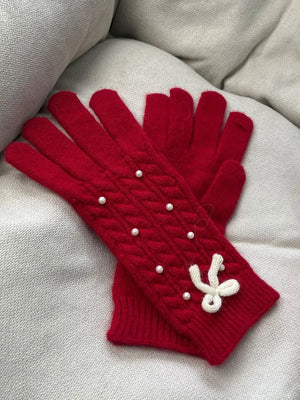 Red cable knit gloves with pearl embellishments and a white bow detail.