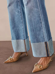 Distressed high-waisted flare jeans with raw hem and cuffed legs in light wash denim.