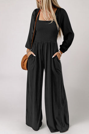 Black smocked bodice wide leg jumpsuit with square neckline and long sleeves.
