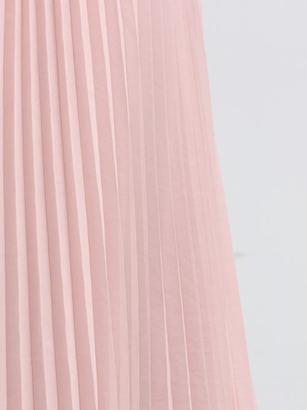 Pink pleated skirt detail of a two-piece ensemble