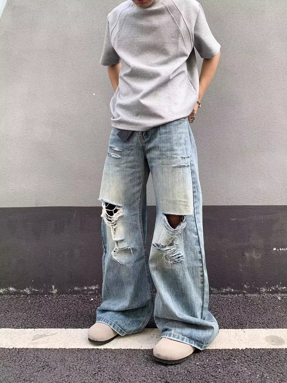 Distressed light wash wide-leg jeans with pocket detail and ripped knees.