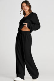 Black relaxed V-neck lounge set with seam detail on wide-leg pants and drawstring waist.