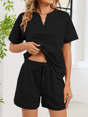 Black loungewear shorts with drawstring waist and cuffed hem, paired with a matching V-neck top.