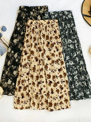 Botanical pleated midi skirts in black, tan, and olive with crinkled fabric and floral print.