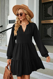 Black textured babydoll mini dress with voluminous sleeves and tiered hem