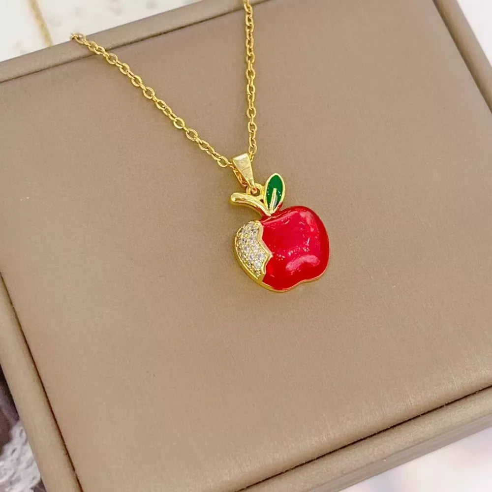 Gold-plated necklace with red apple pendant, green leaf, and crystal accents.