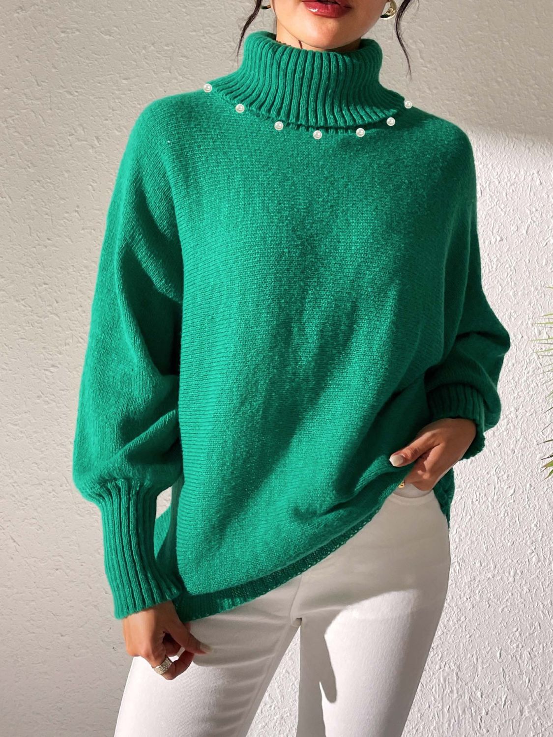 Green knit sweater with pearl-embellished turtleneck and dolman sleeves.