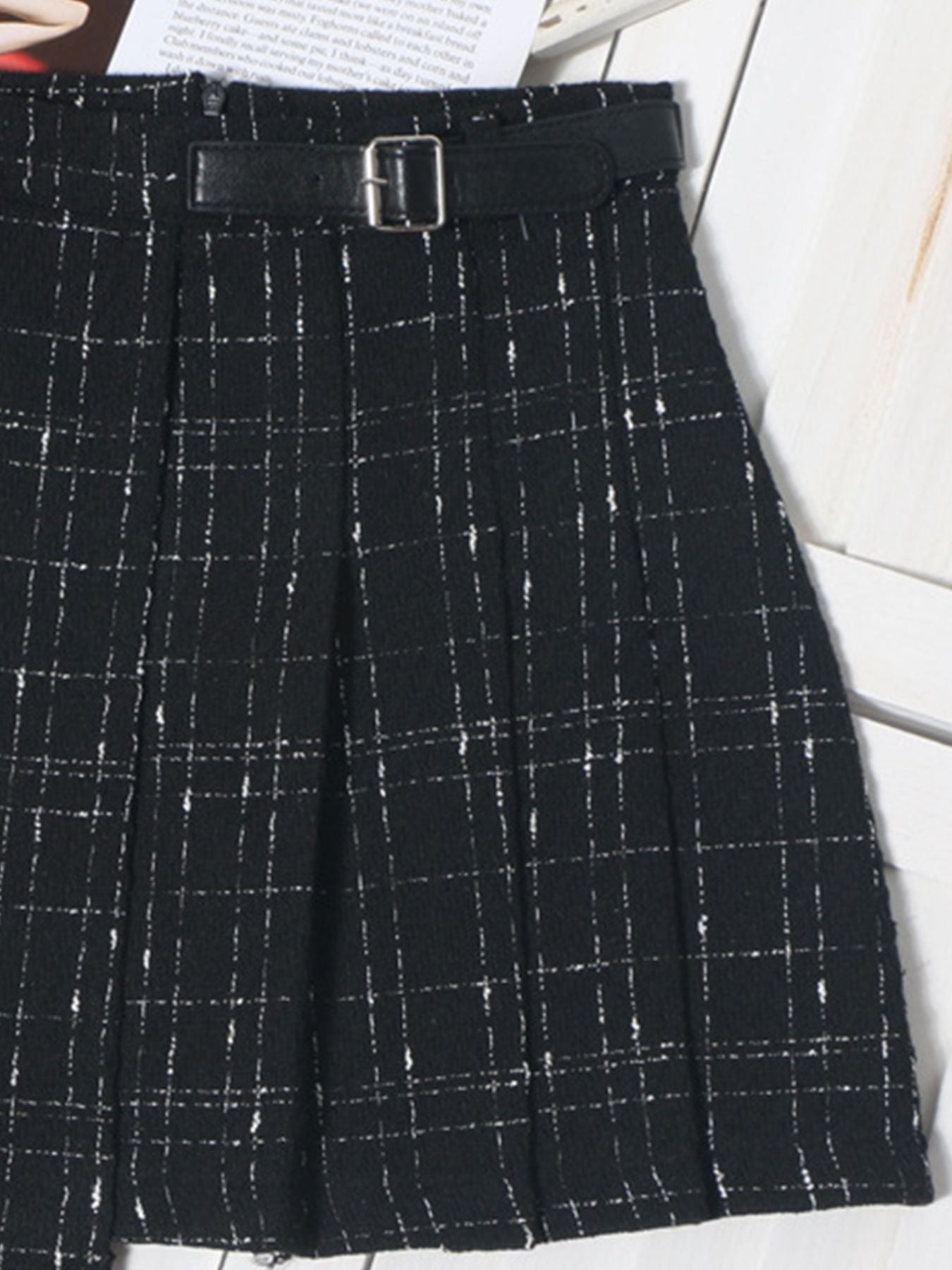 Black plaid mini skirt with a belted waist and ruched detail.