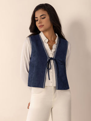 Dark blue suede-effect vest with stitch trim and tie closure, worn over a white shirt.