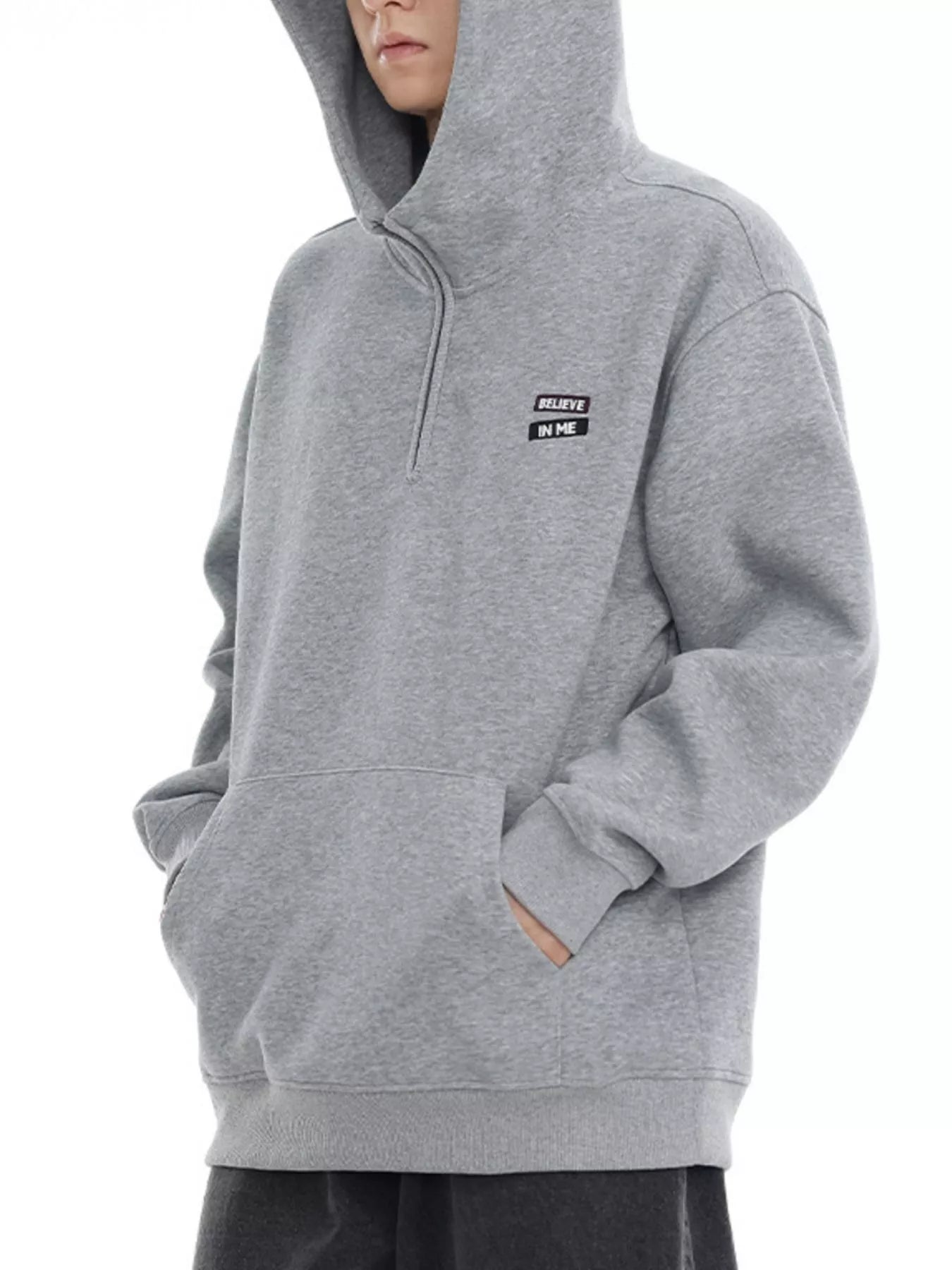 Plus-size grey quarter-zip hoodie with a small "BELIEVE IN ME" patch detail.