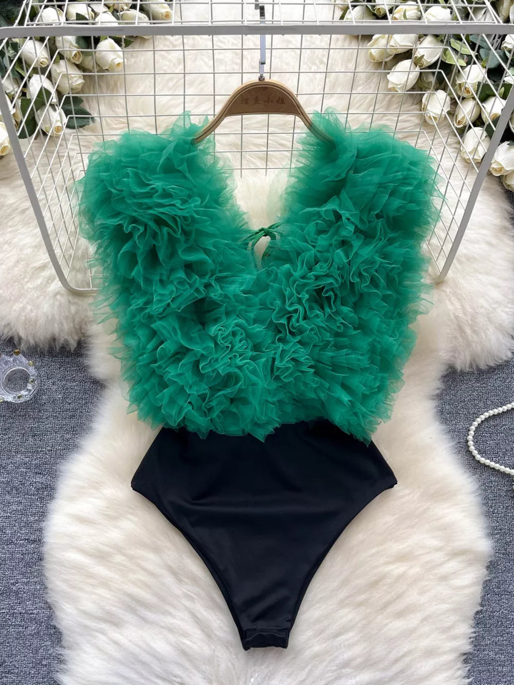 Green ruffled V-neck bodysuit with lace detail and black bottom