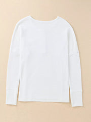 White textured cotton henley shirt with long sleeves and button detail.