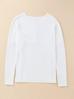 White textured cotton henley shirt with long sleeves and button detail.