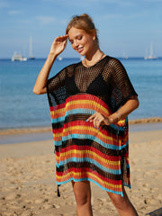 Black crochet beach poncho with rainbow stripes, short sleeves, and tasseled hem.