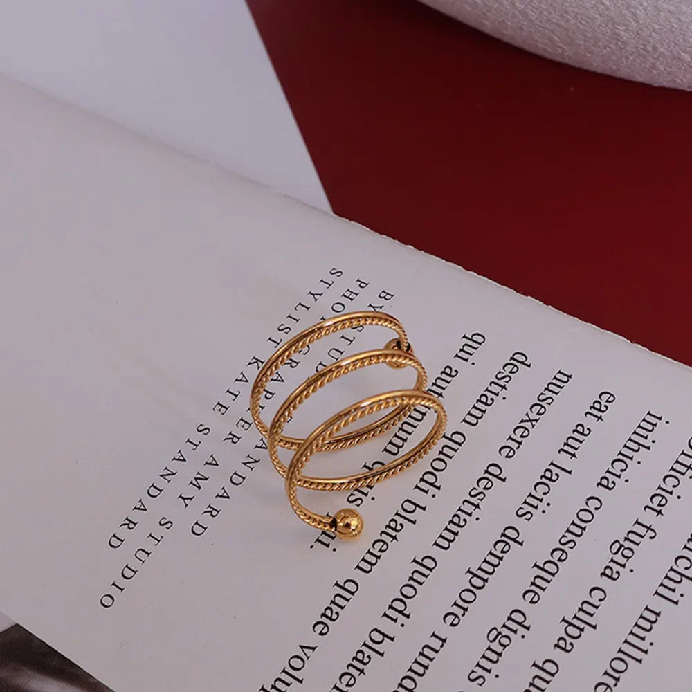 Gold spiral orb ring with twisted bands and a small bead detail.