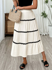 Elegant tiered midi skirt in beige with wavy black trim detail.