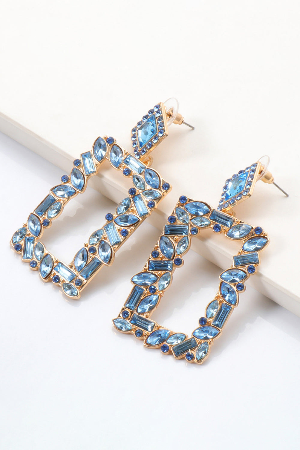 Geometric jewel box earrings with blue stones and gold alloy setting.