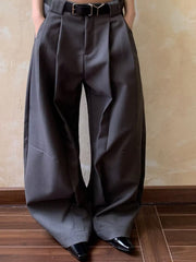 Men's gray wide leg pleated sweatpants with a black belt and pockets.