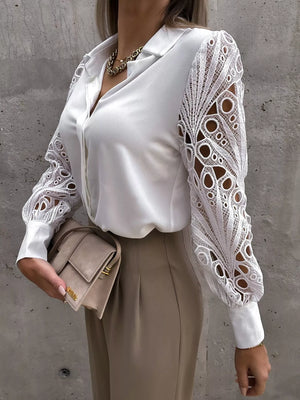 White collared blouse with intricate lace cutout sleeves and buttoned front.