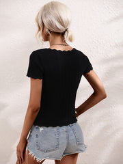Black knit top with scalloped square neckline and short sleeves, styled with denim shorts.