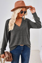 Relaxed V-neck tunic top in dark gray heather with long sleeves, styled with jeans and a hat.