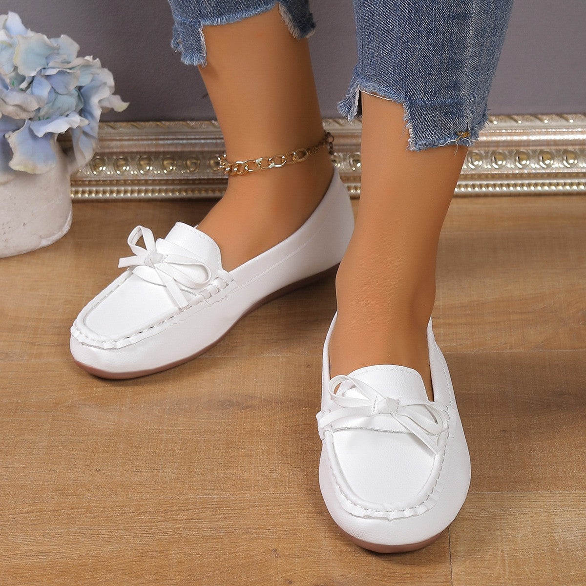 White bow embellished flat slip-on loafers with a gold chain anklet.