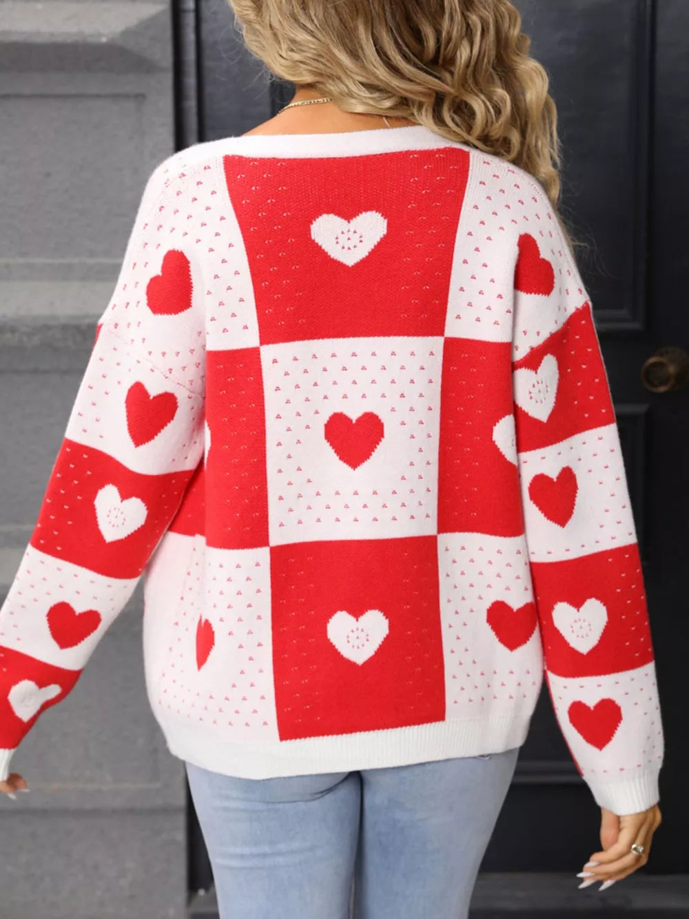 Red and white heart motif knit cardigan with checkered pattern and long sleeves.
