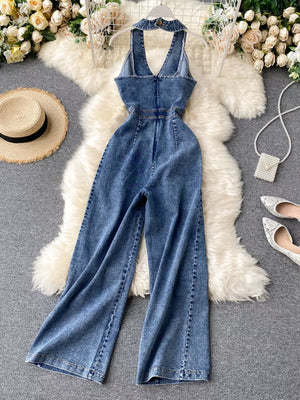 Chic denim halter neck wide-leg jumpsuit in blue with button detail and V-neck.