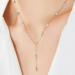Silver lariat necklace with scattered moissanite stones and a drop pendant detail.