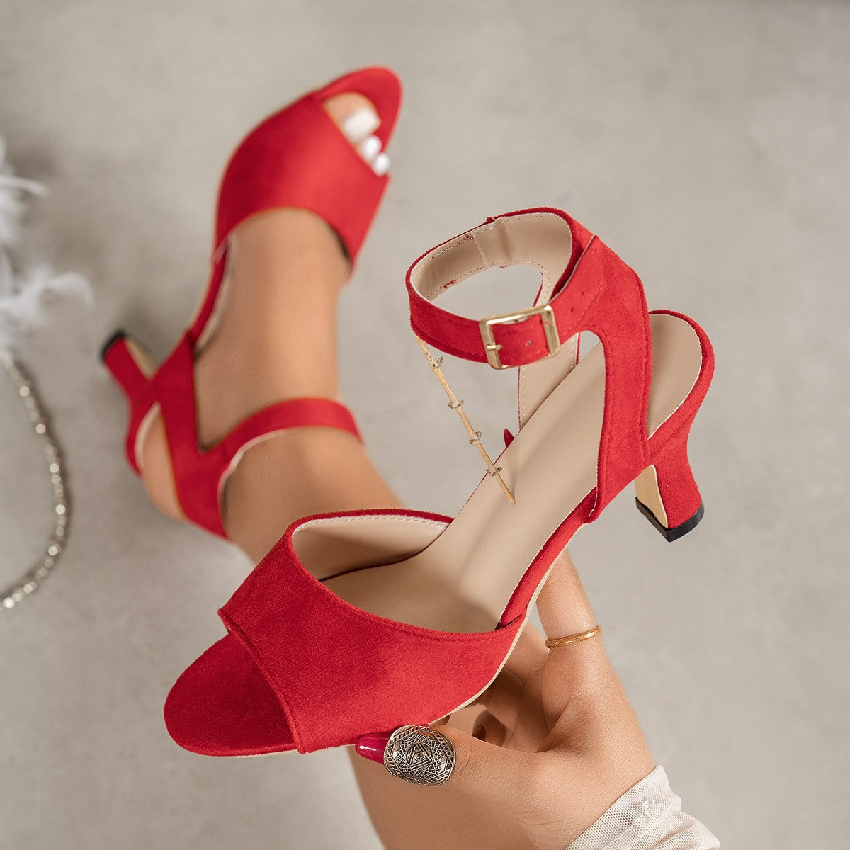 Red suede ankle strap block heel sandals with peep toe and gold buckle.