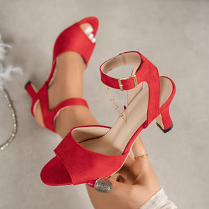 Red suede ankle strap block heel sandals with peep toe and gold buckle.
