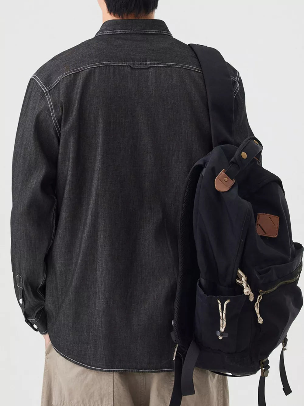 Black denim button-up shirt with chest pockets and white contrast stitching.