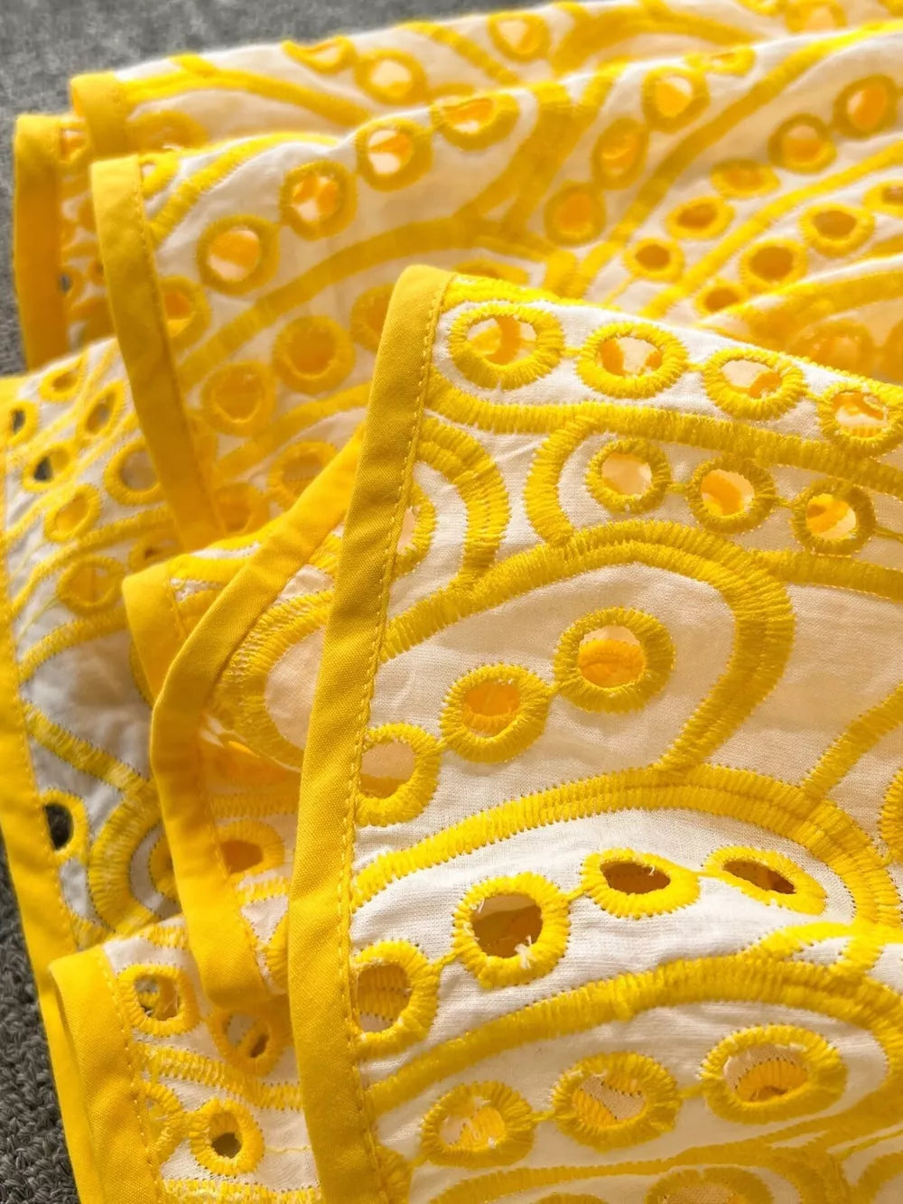 Yellow lace-embroidered cami dress with eyelet details and tiered design.
